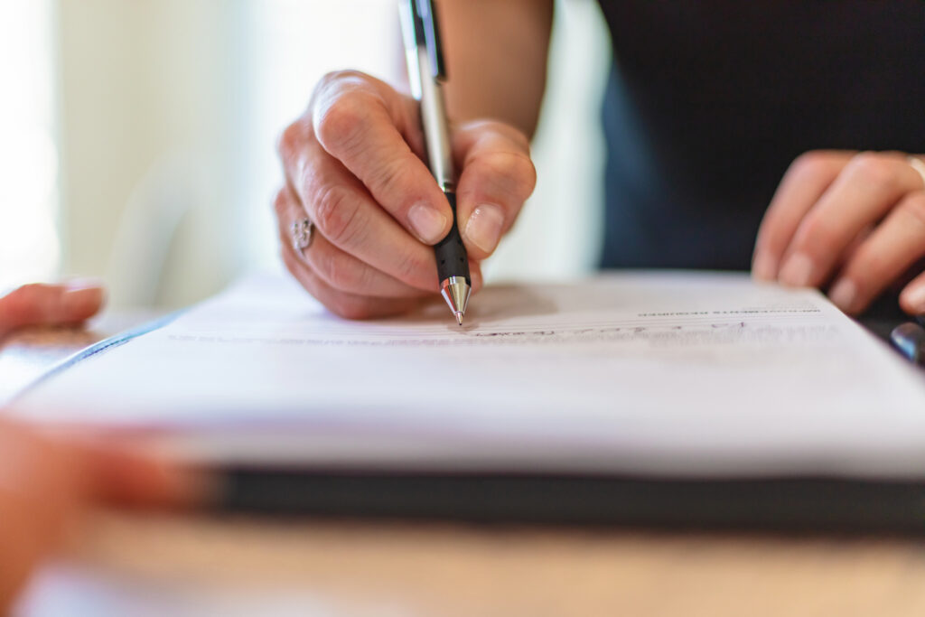 A business owner drafts a franchise risk management plan using a pen in a meeting.